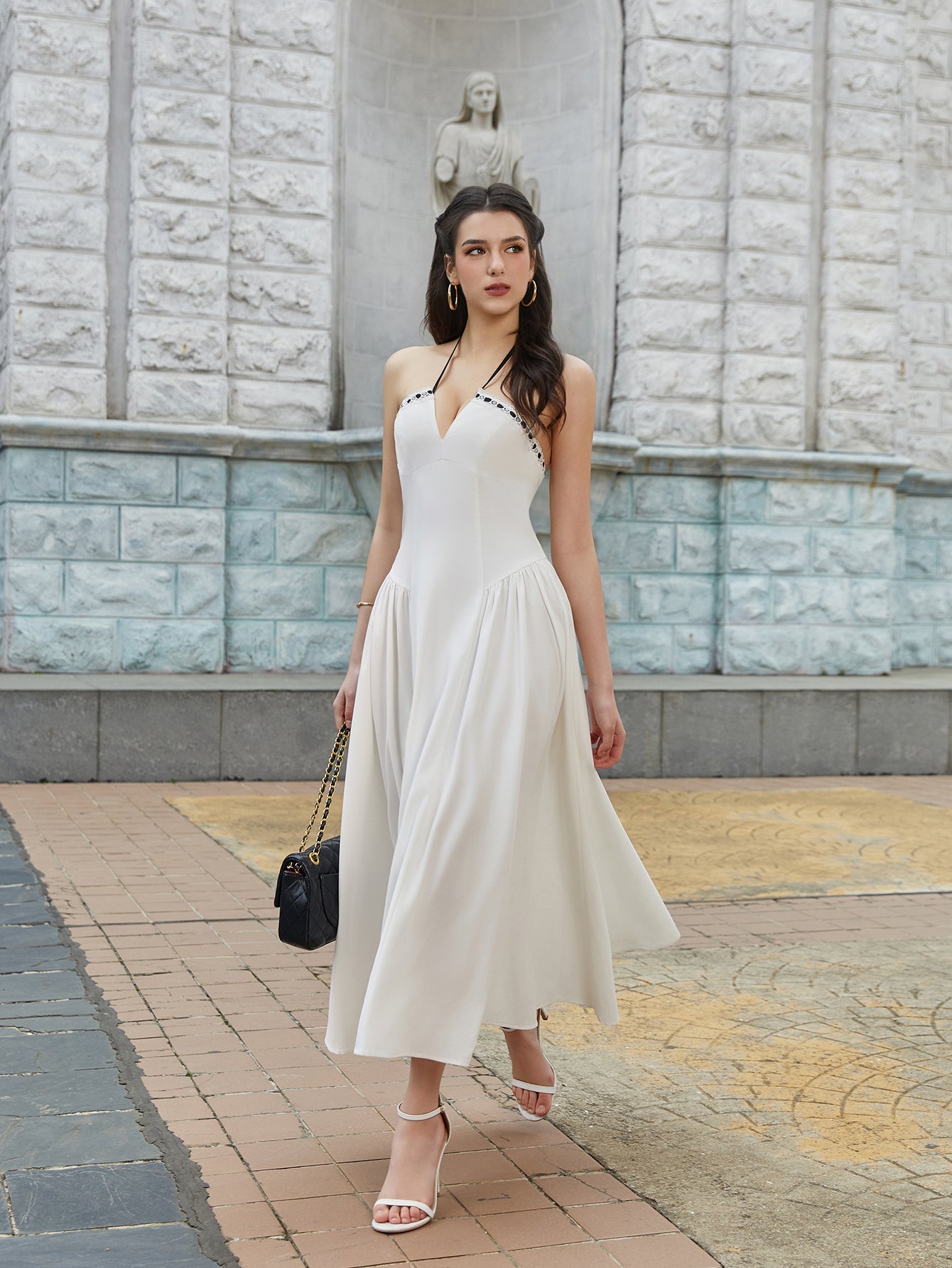 Woman walking in a white halter midi dress with contrast trim, outdoors