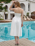 Back view of a woman in a white strapless midi dress with a tie-back detail.