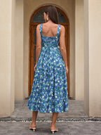 Back view of a woman in a blue floral print midi dress with a square neckline and wide straps.
