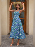 Woman posing with a straw hat, wearing a blue floral print midi dress with a square neckline.