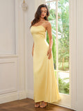 Full body shot of a woman in a yellow satin maxi dress with spaghetti straps.