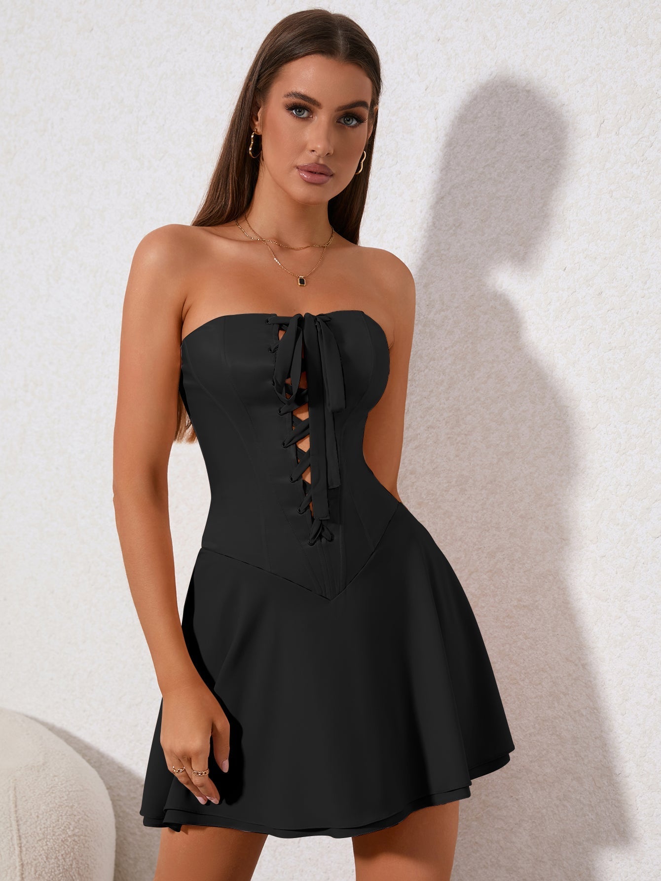 Front view of a woman wearing a black strapless corset dress with a flared skirt
