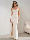 Side profile of a woman wearing a white floor-length gown with a thigh-high slit.