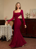 Woman in a long-sleeved, burgundy, sequined gown with a square neckline and a high slit, smiling and turning to the side.