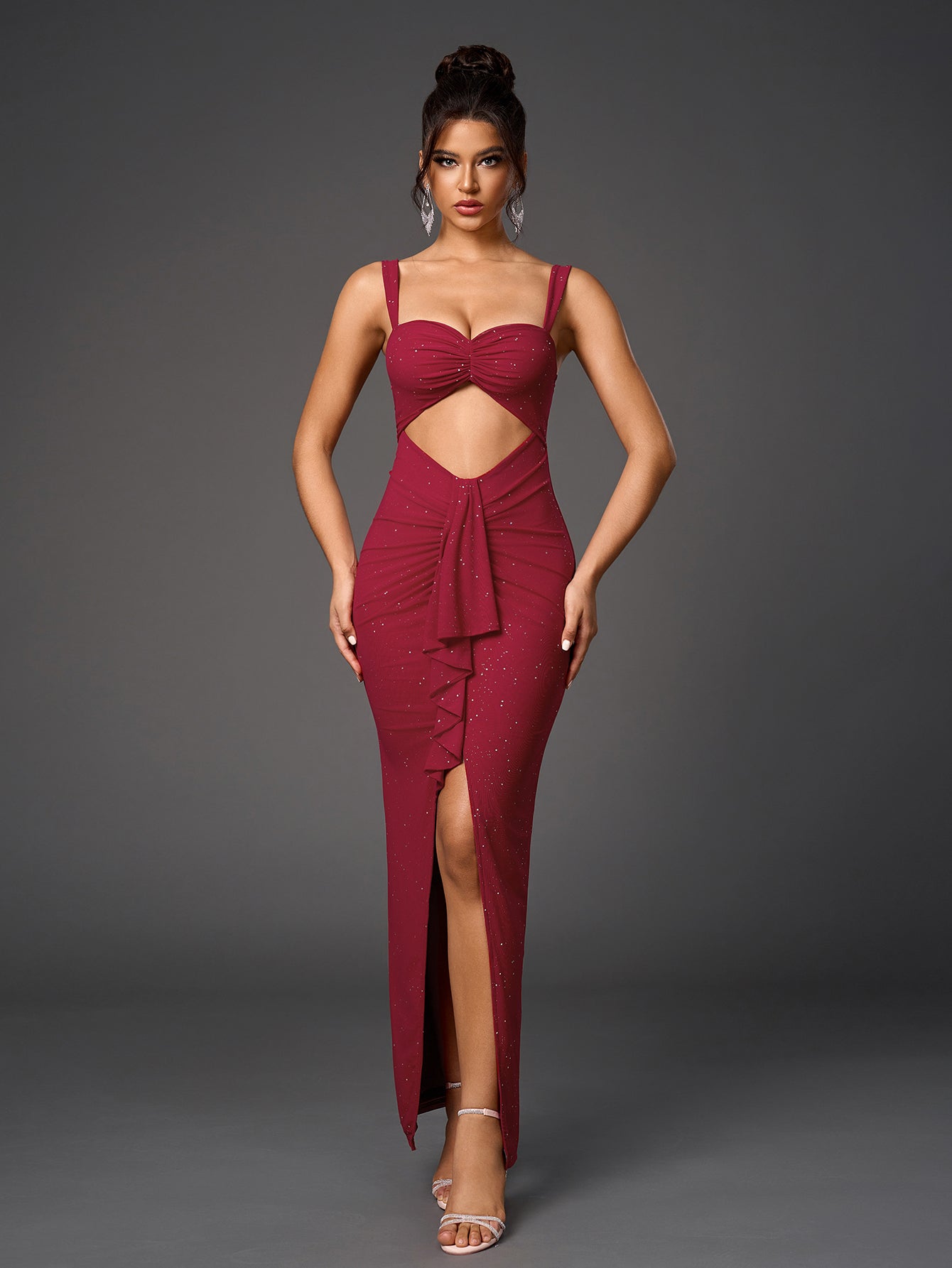 Full-body image of a woman presenting a sophisticated deep red evening gown with a cutout, ruching, a high slit, and sparkling details.