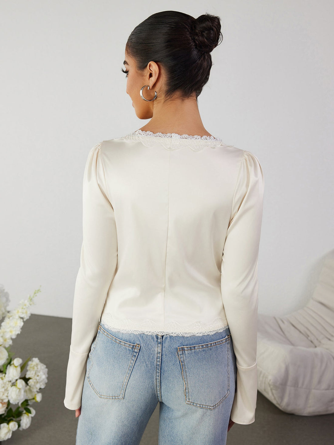 Woman wearing an ivory lace trim tie front top with jeans