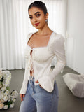 Model posing in an ivory lace trim tie front top