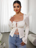 Close up of the lace trim and tie front detail on an ivory top