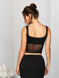 Back view of a model in a black cropped top with a textured knit bodice and a sheer mesh back panel.