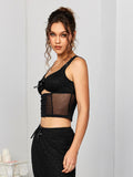 Side profile of a model wearing a black textured knit cropped top with a sheer mesh insert and a cutout detail.