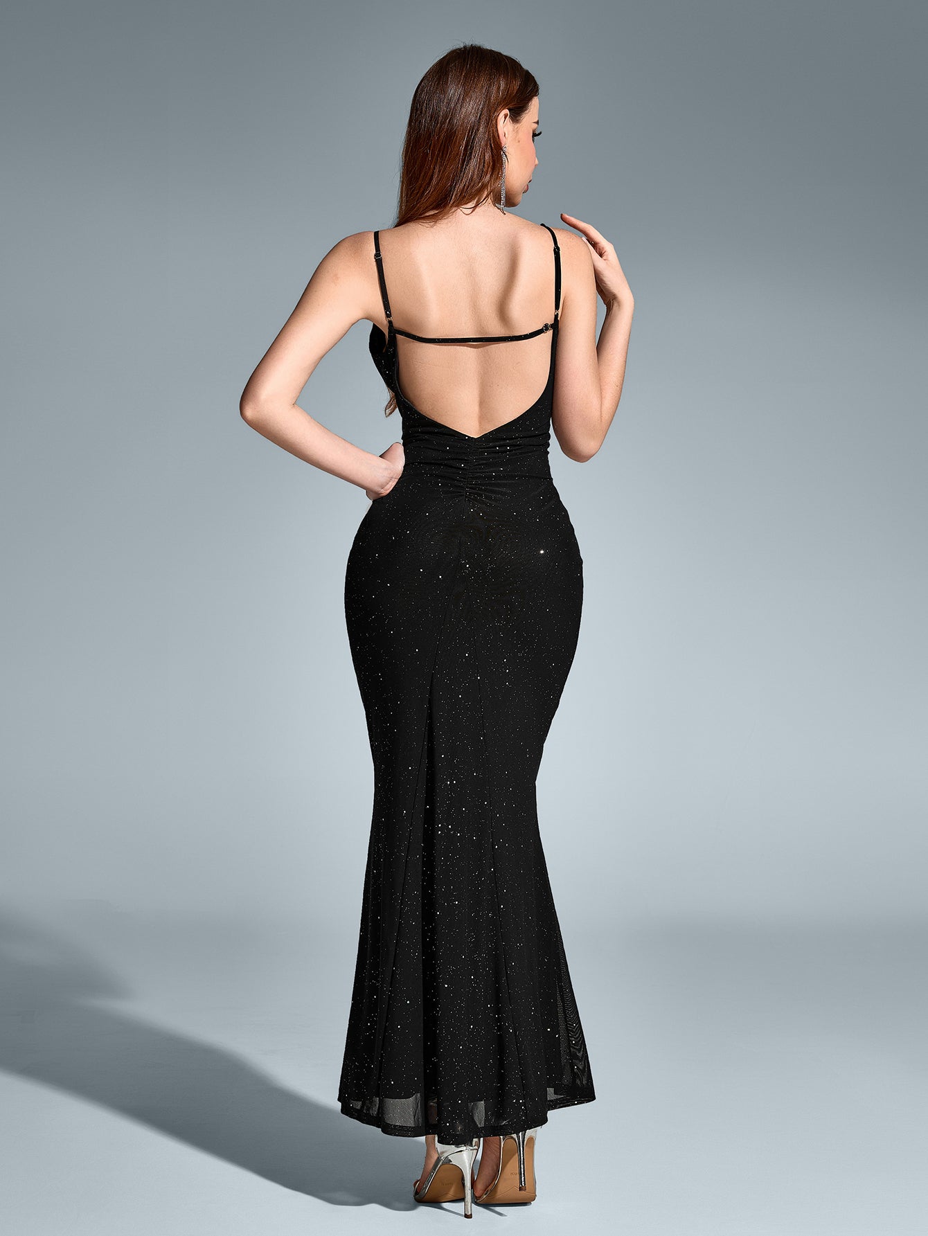 Back view of a woman in a black sequin maxi dress with an open-back design