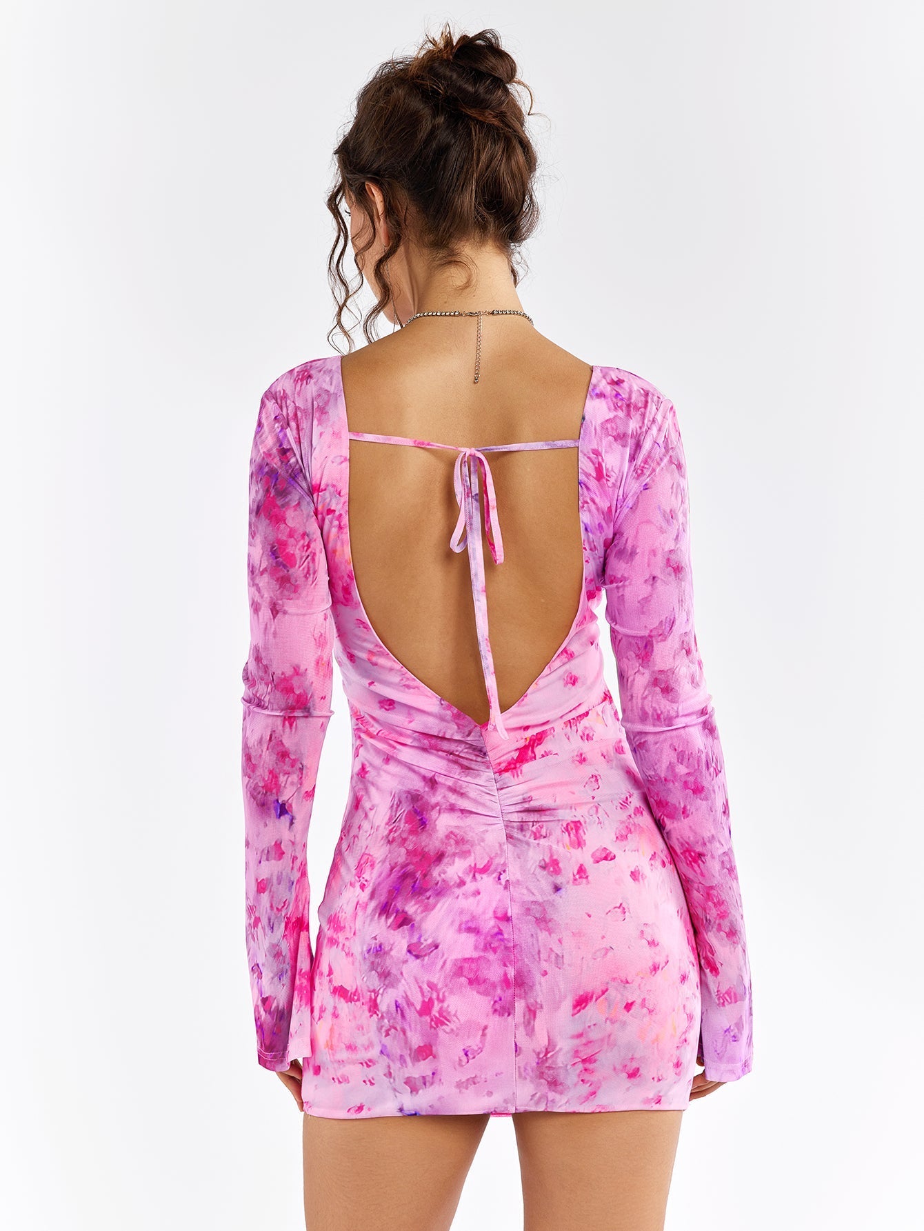 Back view of a pink floral print mini dress with an open back and tie closure