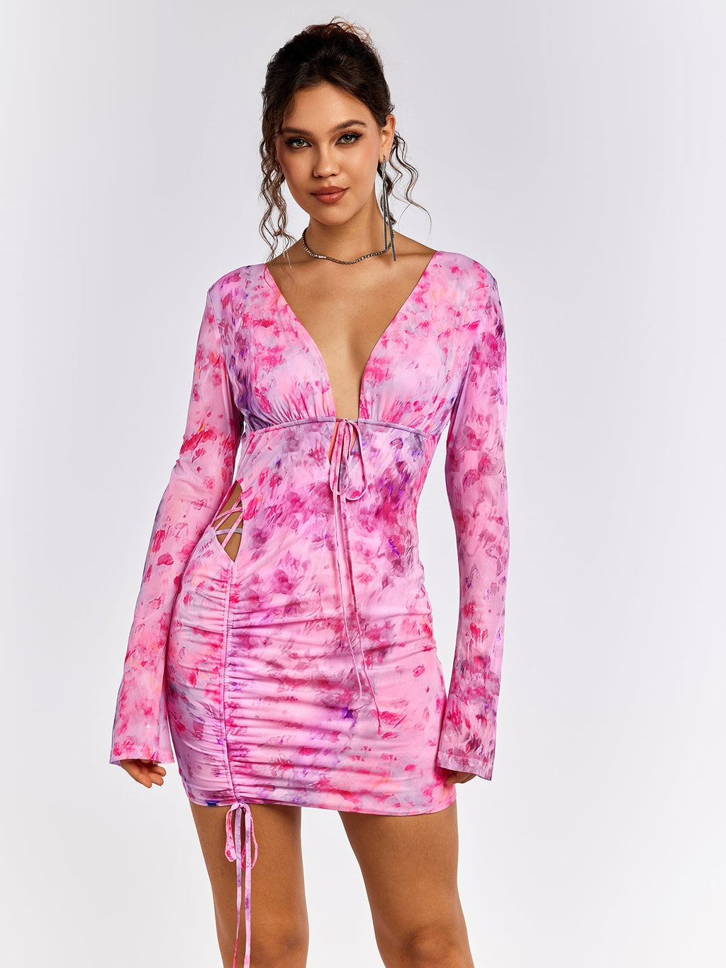 Woman wearing a pink floral print mini dress with a V-neckline and tie detail