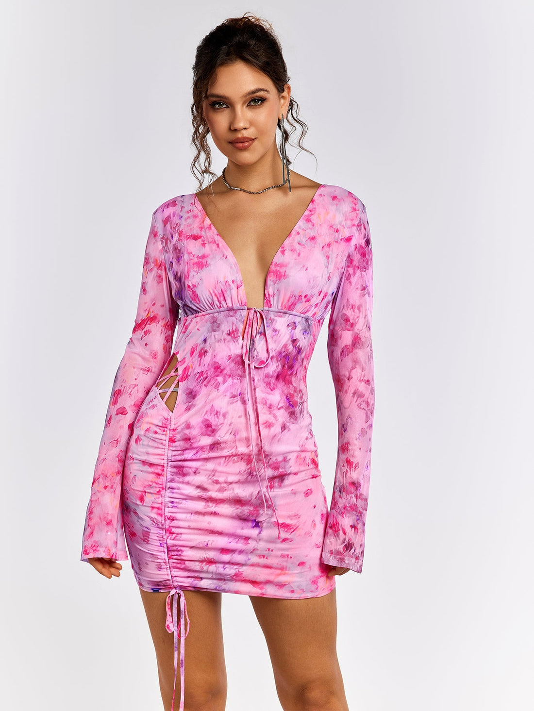 Woman wearing a pink floral print mini dress with a V-neckline and tie detail