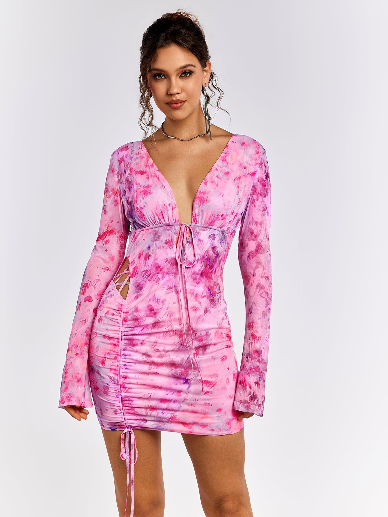 Woman wearing a pink floral print mini dress with a V-neckline and tie detail