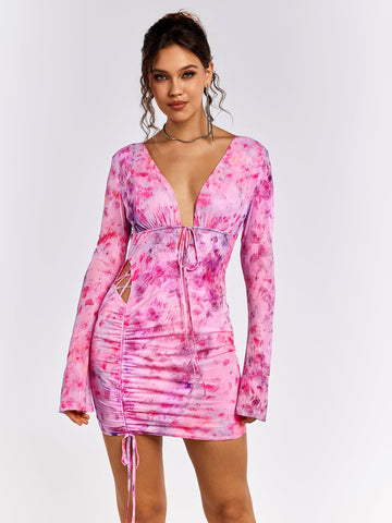 Woman wearing a pink floral print mini dress with a V-neckline and tie detail