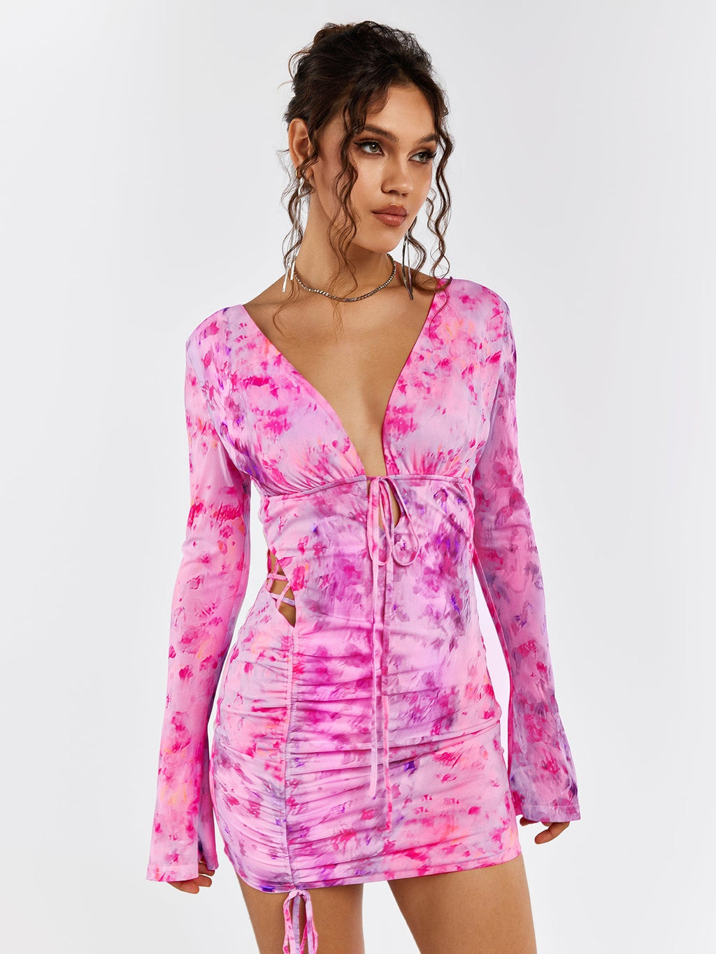 Model posing in a pink floral print mini dress with long flounce sleeves
