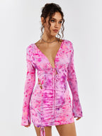 Model posing in a pink floral print mini dress with long flounce sleeves