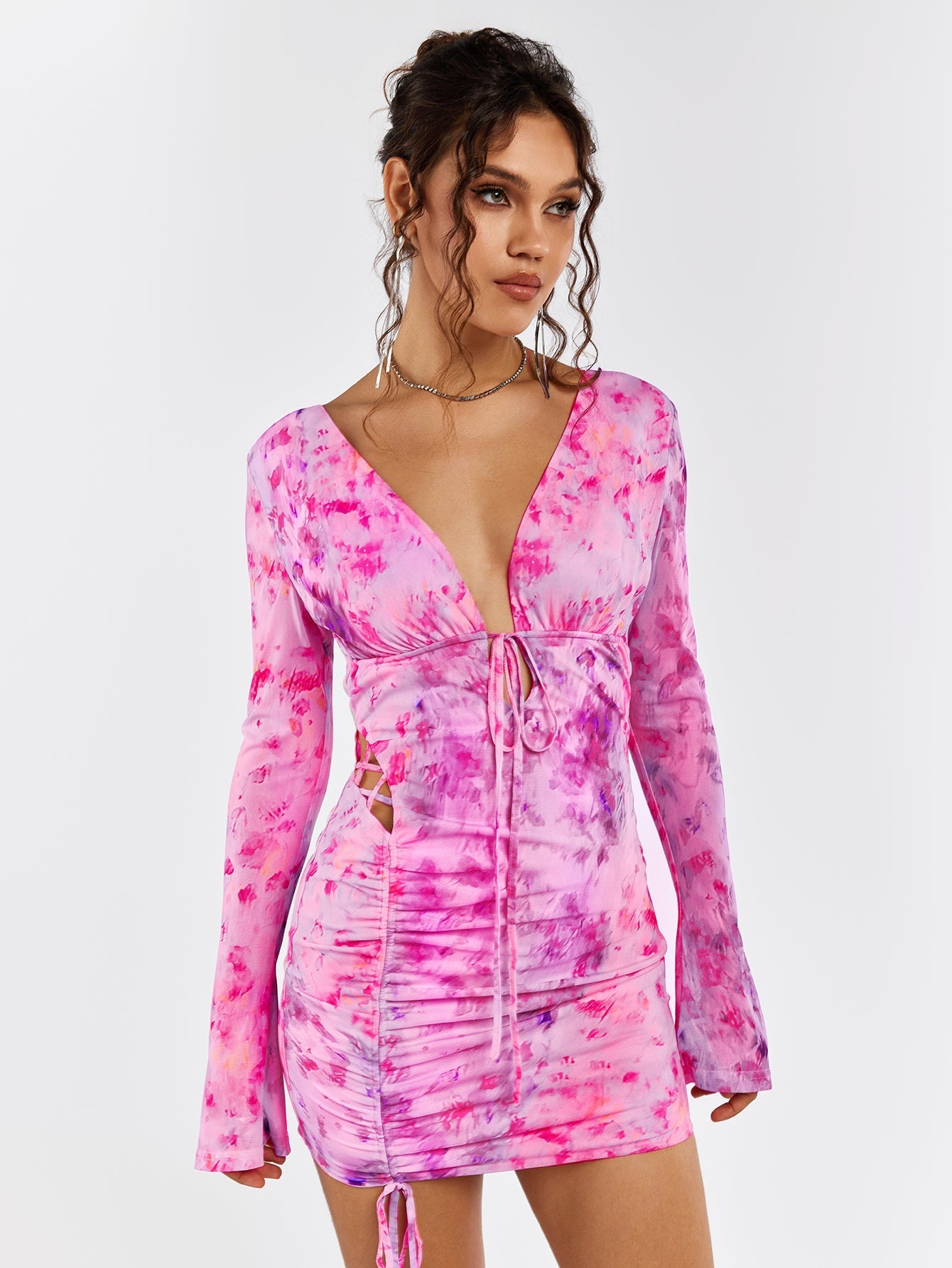Model posing in a pink floral print mini dress with long flounce sleeves