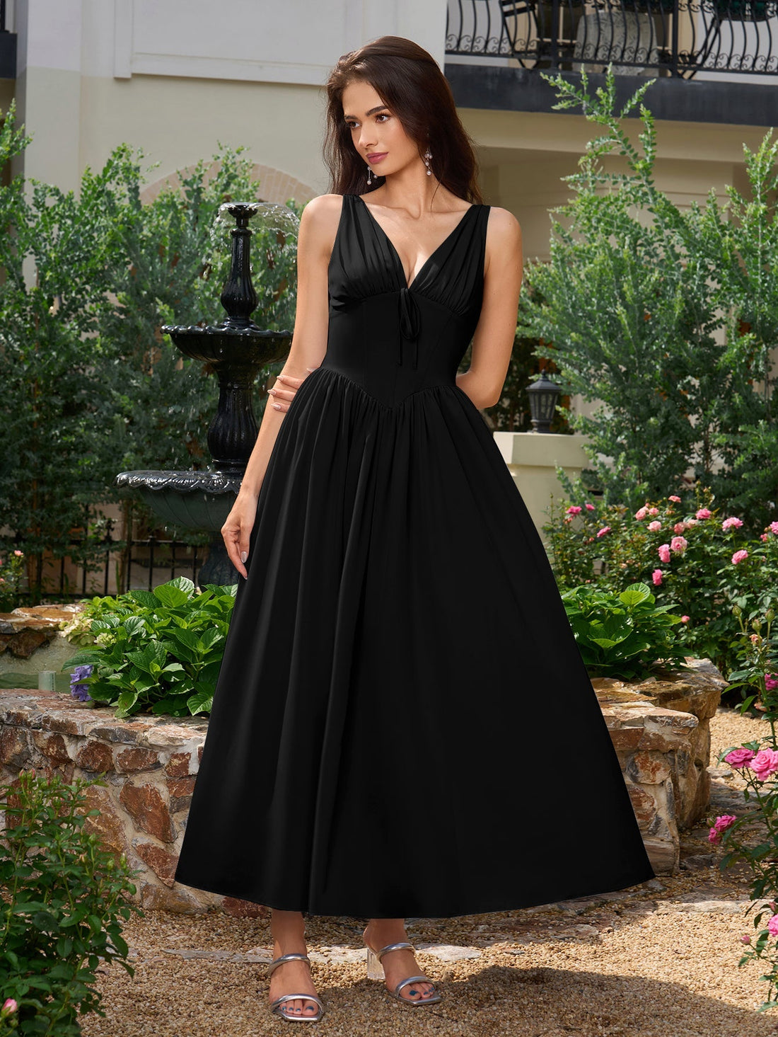 Model wearing a black V-neck midi dress with a bow tie detail and pockets.