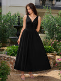 Model wearing a black V-neck midi dress with a bow tie detail and pockets.