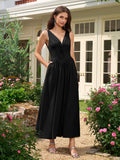 Woman posing in a black V-neck ruched midi dress in a garden setting.