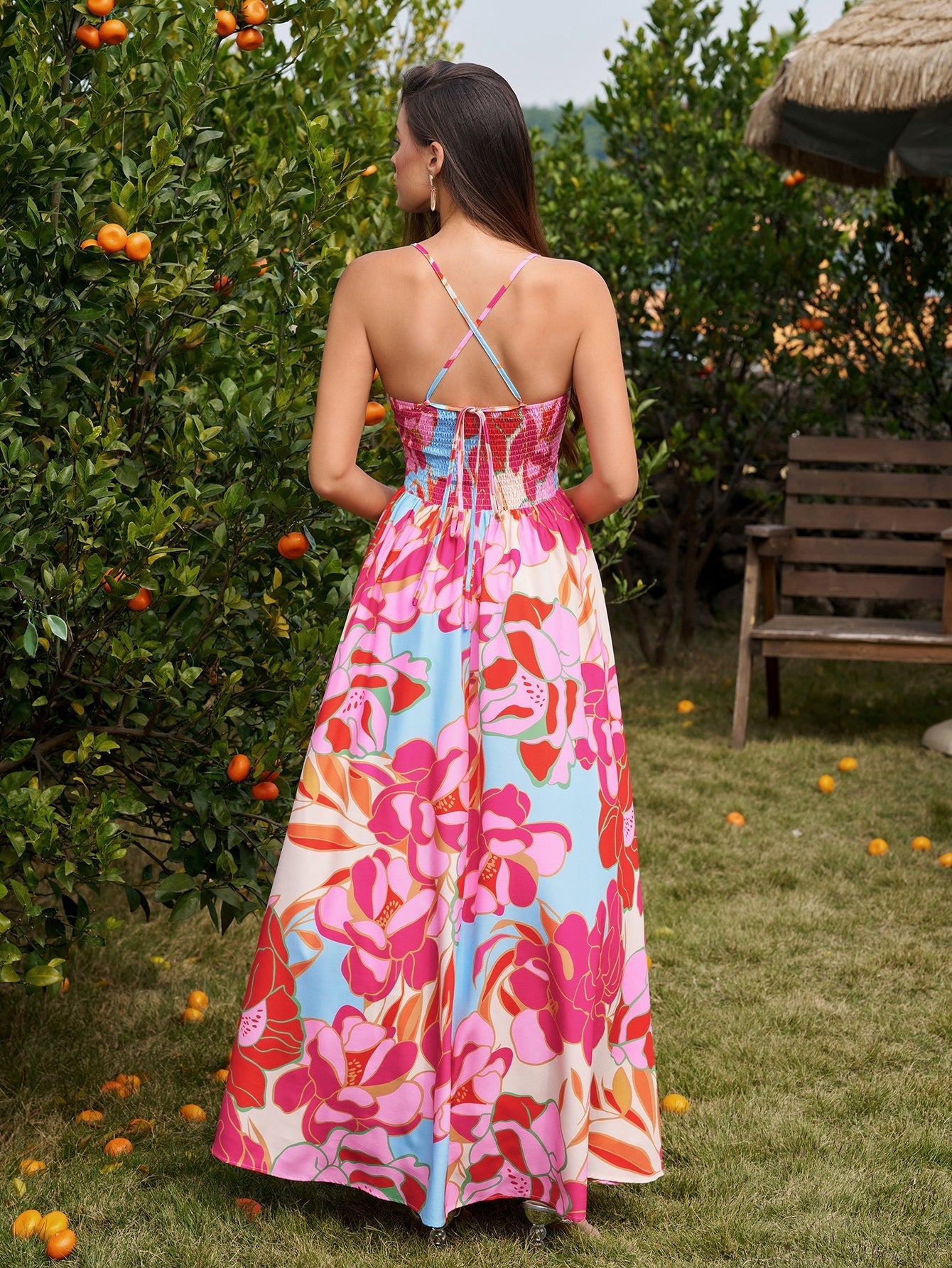 Back view of a woman in a floral print maxi dress showing the crisscross straps and smocked panel