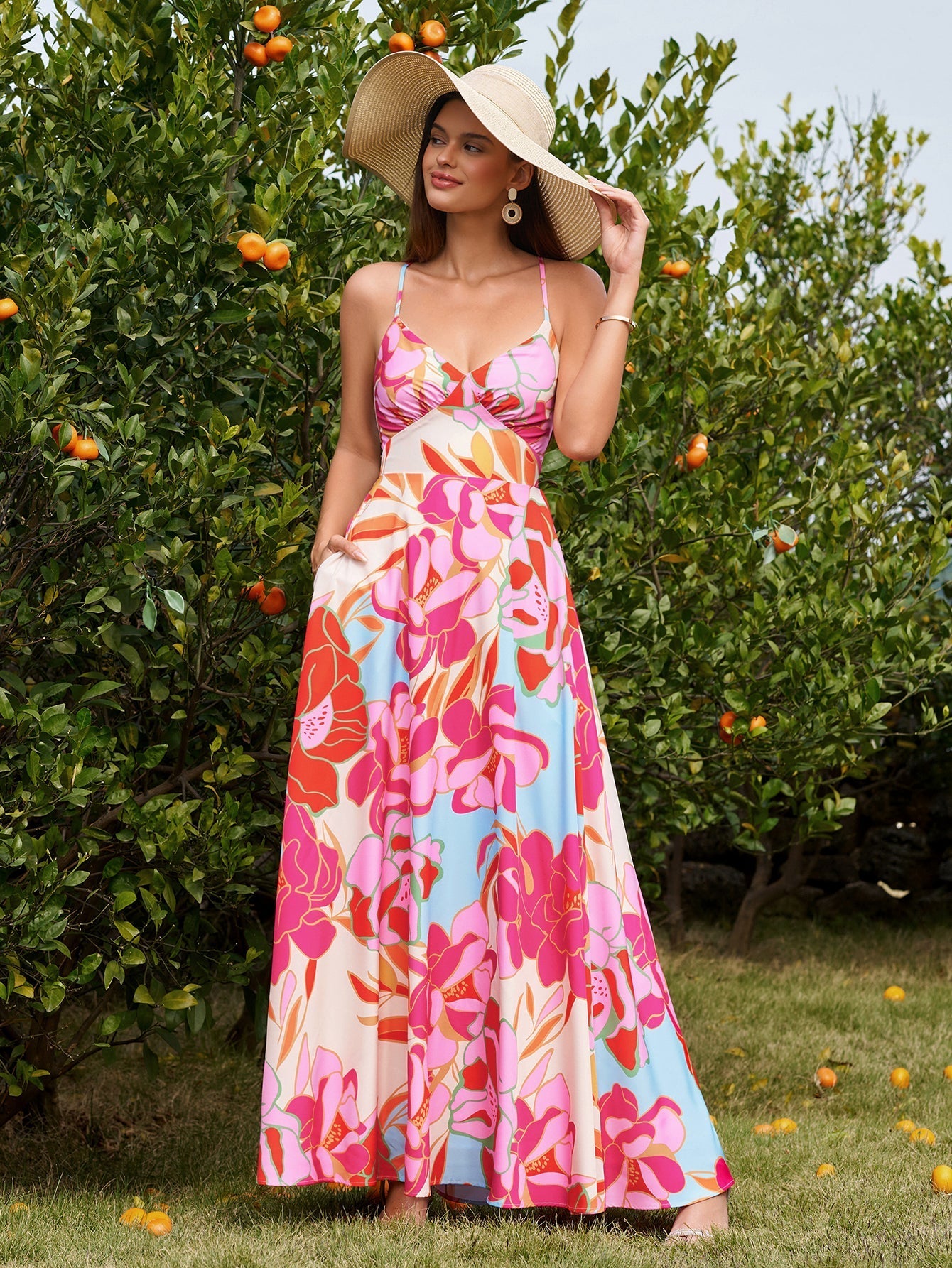 Woman in a straw hat wearing a pink floral print maxi dress outdoors