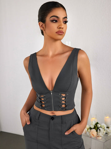 Woman wearing a grey zipper V-neck crop top with lace-up detail