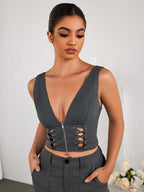 Close-up of the front of a grey V-neck crop top with zipper and lace-up detail