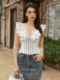 Woman wearing a white and black polka dot tie front top with flounce trim