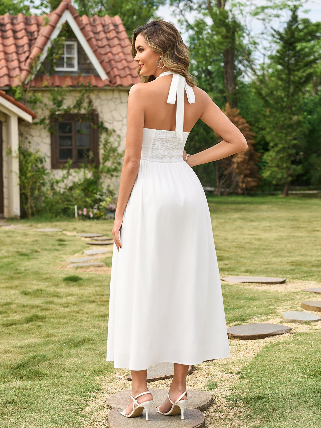 Woman wearing a white halter neck maxi dress with a bow detail outdoors