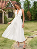 Woman twirling in a white halter neck maxi dress with a bow detail
