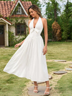 Woman twirling in a white halter neck maxi dress with a bow detail