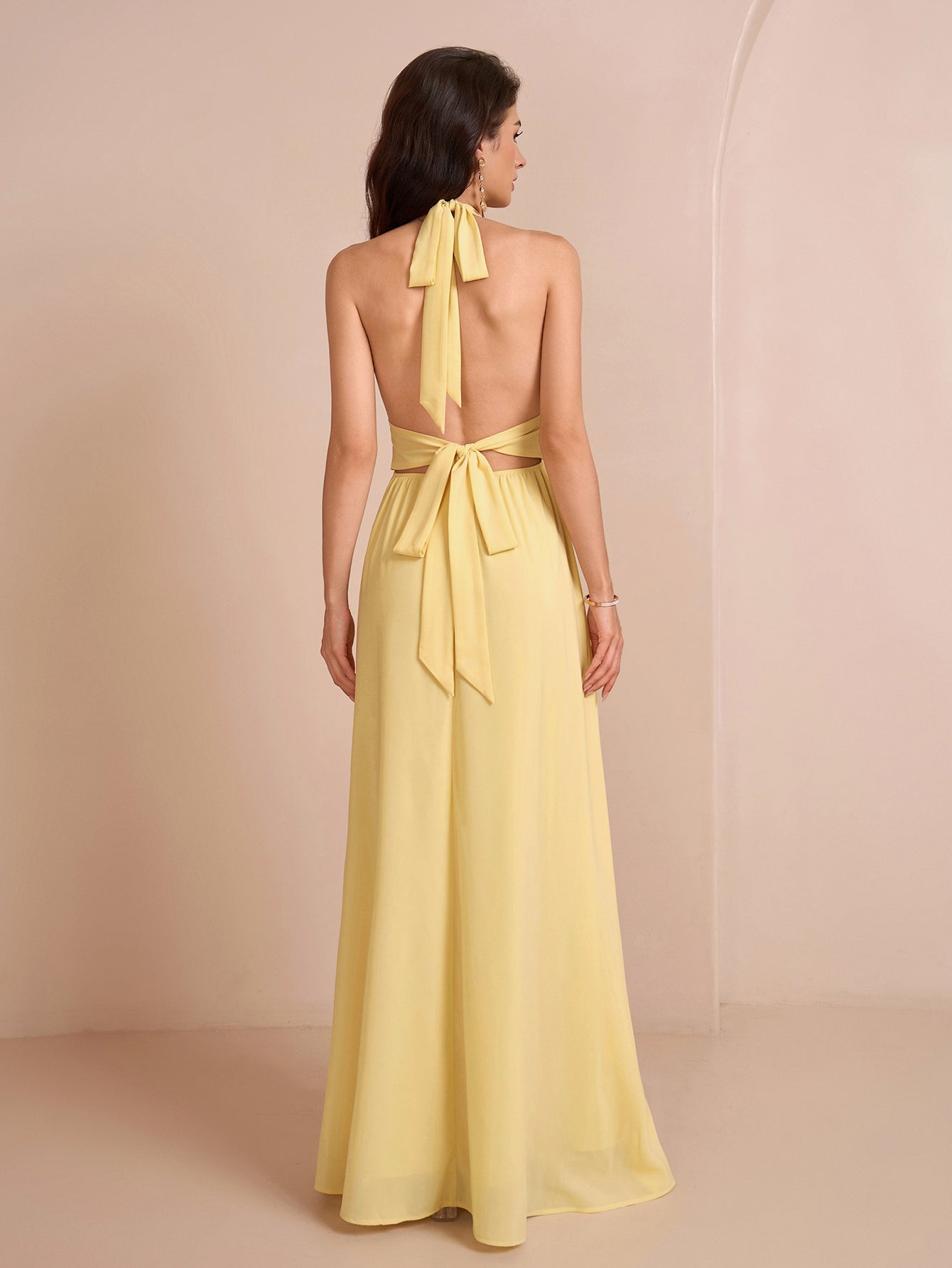 Back view of a yellow halter neck maxi dress showing the bow tie closure
