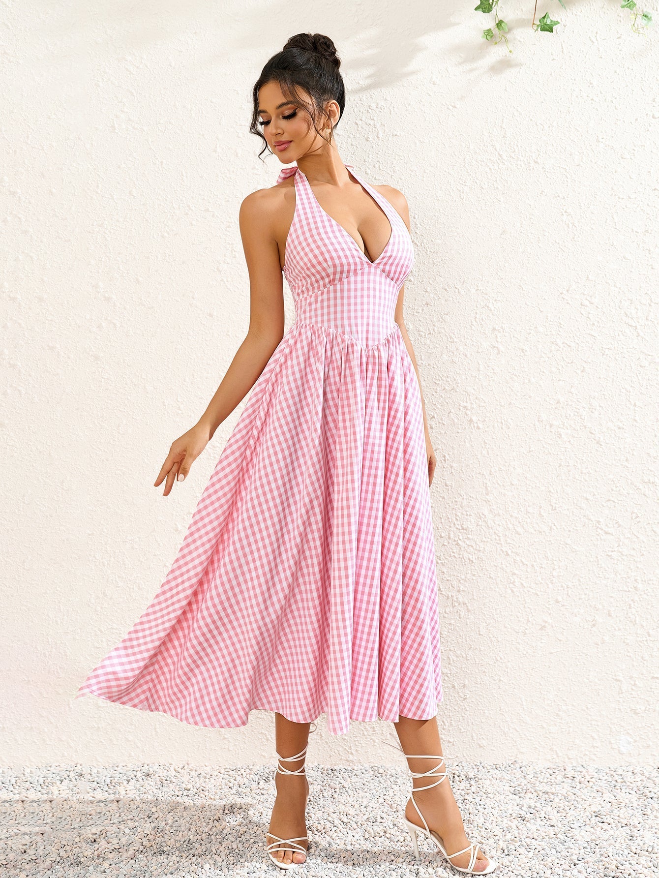 Side view of a woman in a pink plaid halter neck midi dress