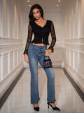 Model posing in a black ruched button-front top and flared jeans
