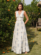 Woman wearing a cream floral print maxi dress with blue flowers and lace trim