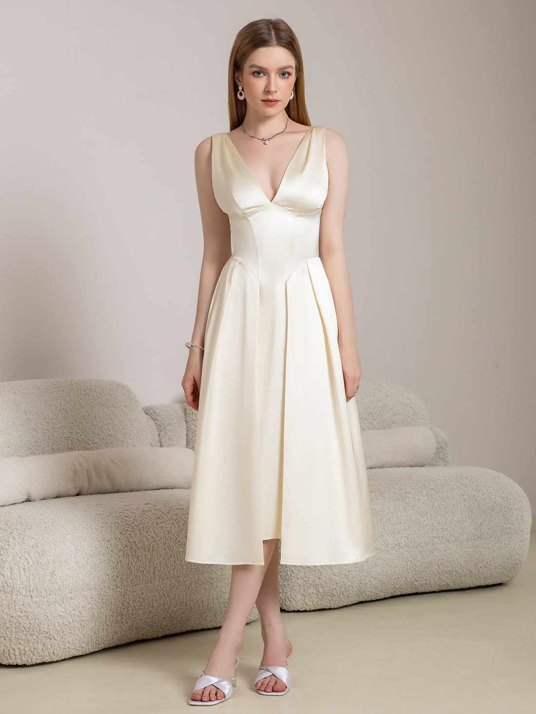Woman wearing a beige satin midi dress with a V-neckline and A-line skirt