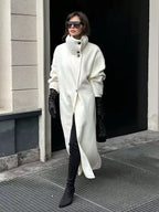 Woman wearing a white wool blend funnel neck long coat with black gloves and sunglasses
