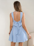 Back view of a woman in a light blue sleeveless cowl neck fit and flare dress with an open back and bow detail.