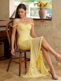 Woman sitting and posing in a yellow ruched asymmetrical hem mesh maxi dress