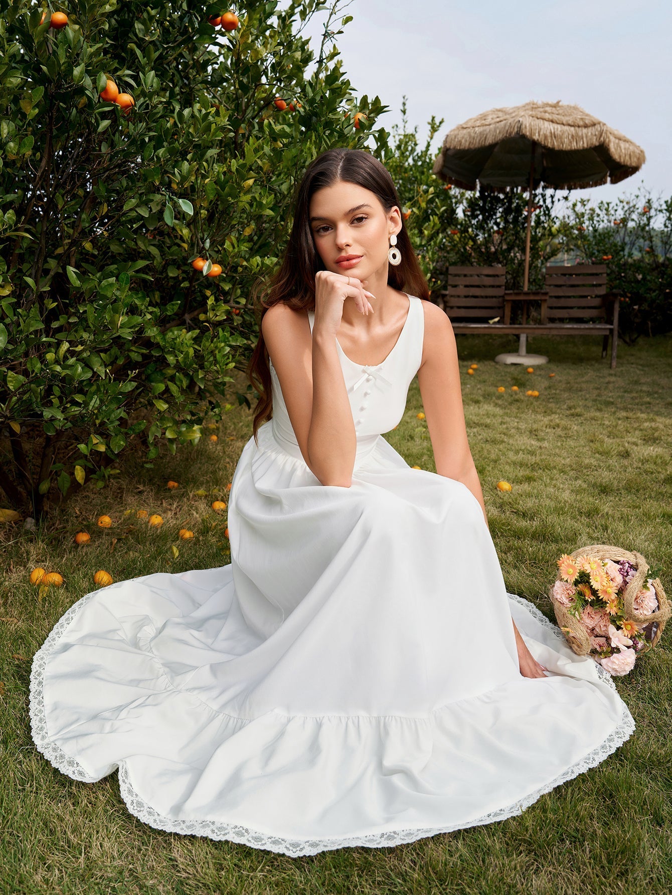 Woman sitting on the grass in a white lace-trimmed maxi dress