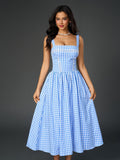 Full-length shot of a woman in a blue plaid midi dress with white bow heels.