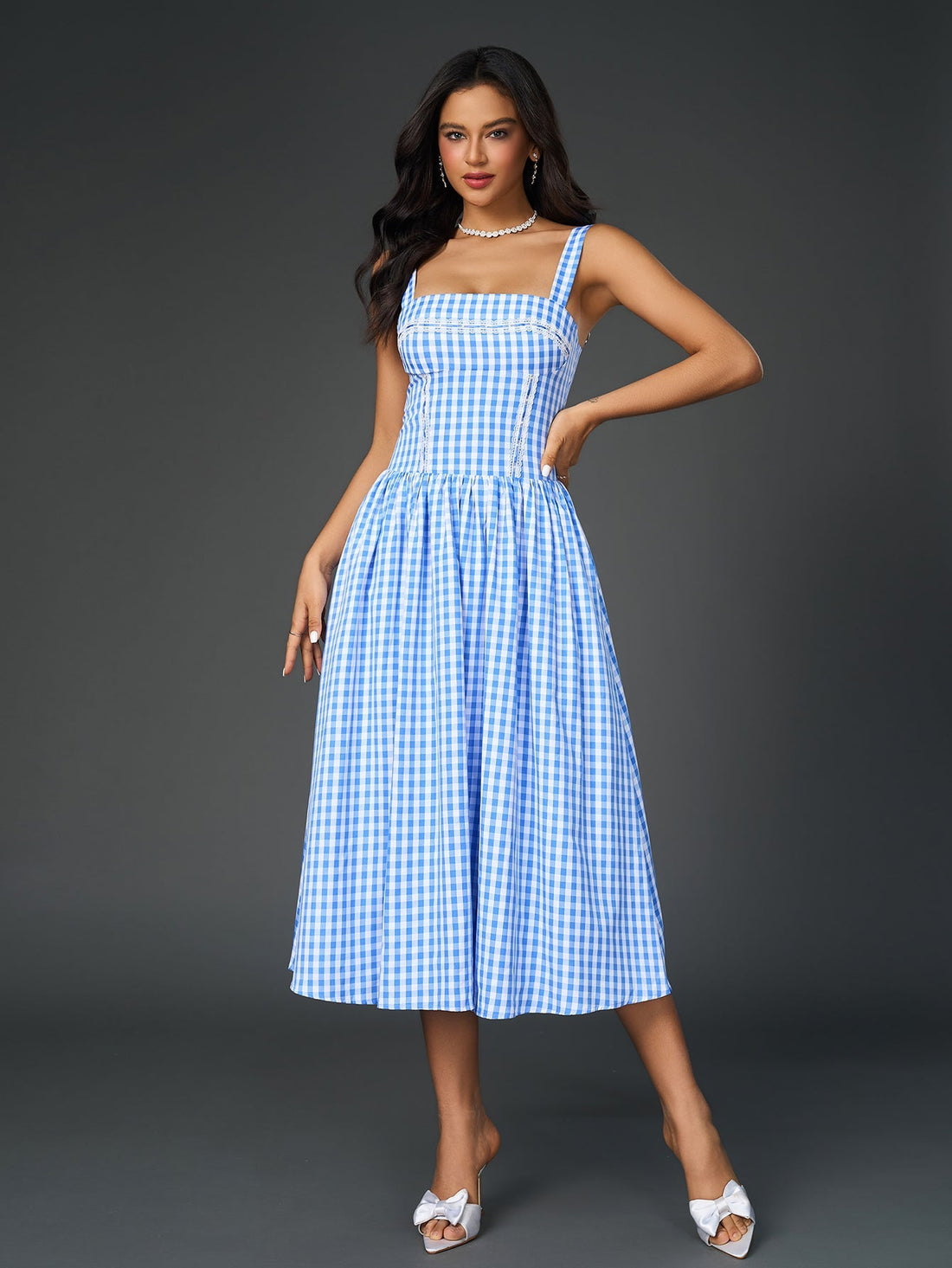 Woman wearing a blue and white plaid midi dress with spaghetti straps and lace trim.