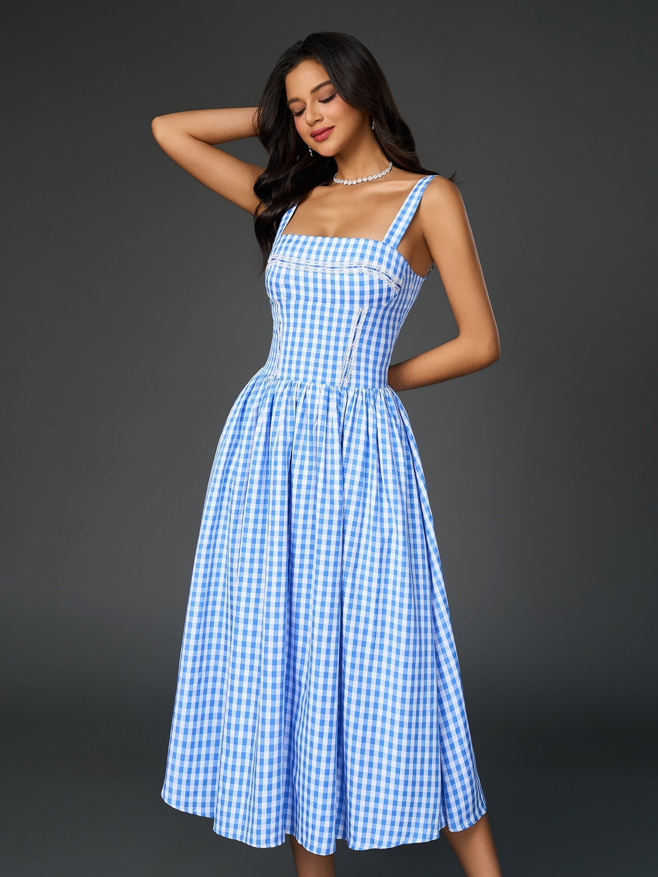Model posing in a blue gingham midi dress with a fitted bodice.