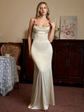 Woman wearing a cream satin evening gown with floral embellished straps and a cowl neckline
