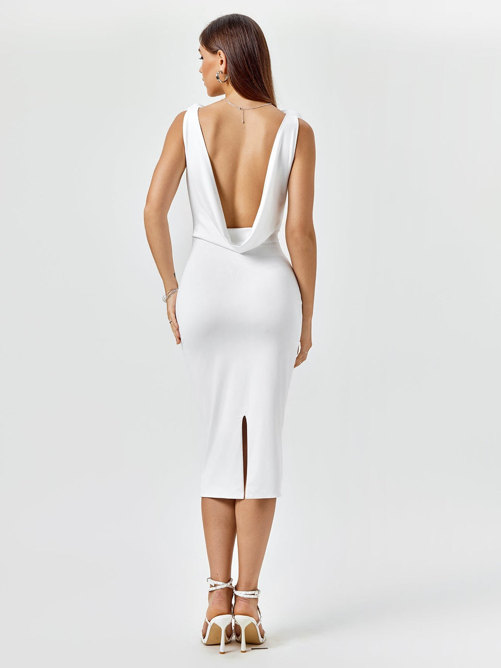 Back view of a white fitted midi dress with an open draped back and side slit