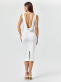 Back view of a white fitted midi dress with an open draped back and side slit