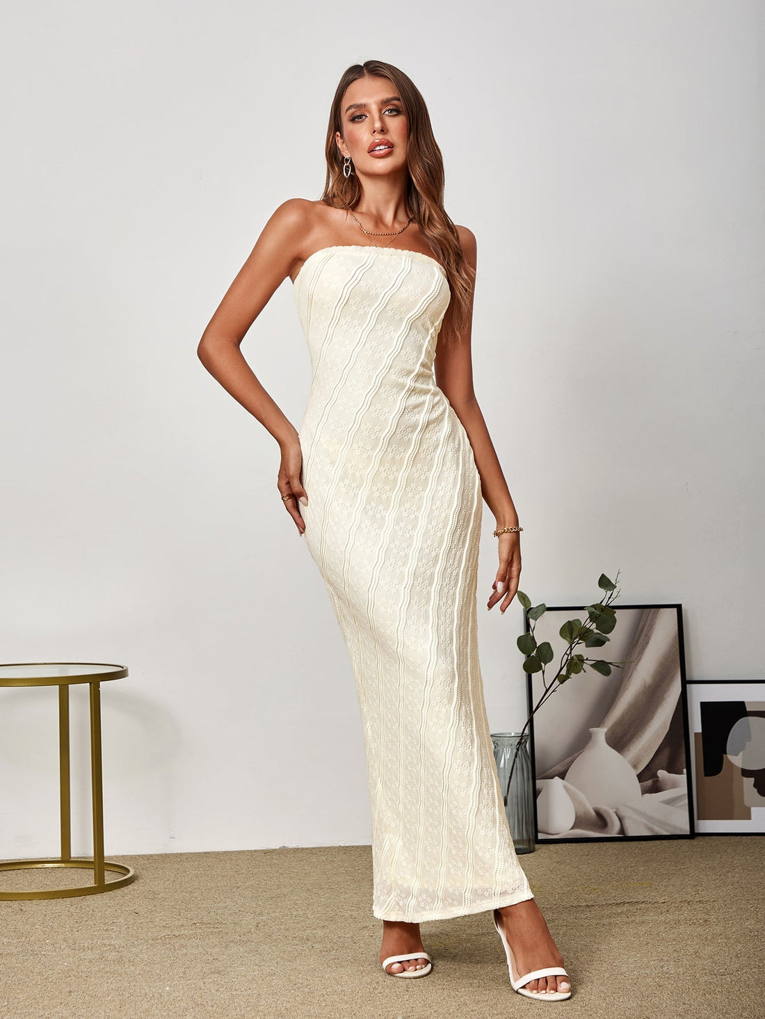 Woman wearing a beige lace strapless maxi dress from the front